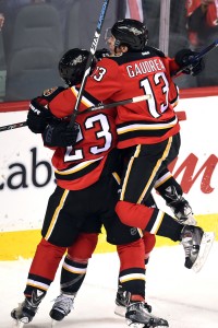 Dec 4, 2015; Calgary, Alberta, CAN; Calgary Flames left wing Johnny Gaudreau (13) jumps on center Jiri Hudler (24) and center Sean Monahan (23) to celebrate Hudler's  goal to tie the game in the third period with  against the Boston Bruins at Scotiabank Saddledome. Flames won 5-4 in overtime. Mandatory Credit: Candice Ward-USA TODAY Sports
